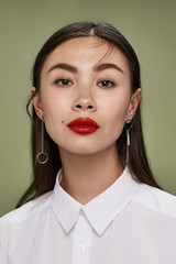 A young Asian woman in a white shirt is looking straight into the camera. The lady is wearing steel...