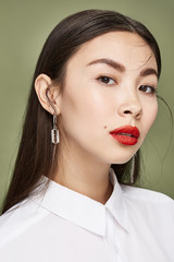 A young Asian woman in a white shirt is looking straight into the camera. The lady is wearing steel...