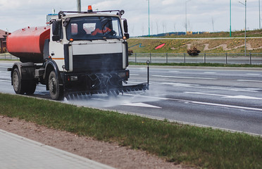 Cleaning machine washes asphalt road surface the city street,