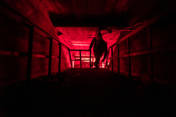 Tunnel of underground communications with man silhouette and red light in the end. Underground...