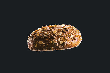 Side view macro of bread isolated on black background. Dark and moody food concept