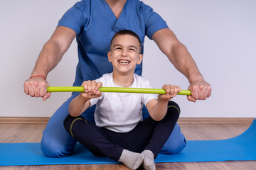Cute kid with disability has musculoskeletal therapy by doing exercises in the hospital.