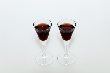 Two small glasses with red wine on a white background