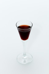Small glass with red wine on a white background