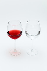 Two glasses on a white table. One is filled with red wine, the other is water.