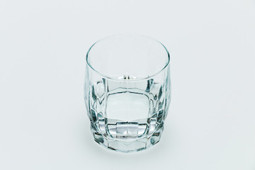 A glass filled with transparent water stands on a table on a white background