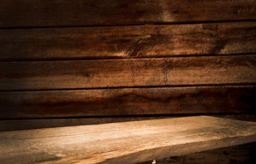 Fototapeta premium Old table top with brown concrete block wall in dark room background.