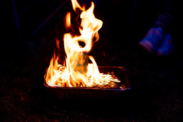 Can of beans cooking on a single use camping grill.