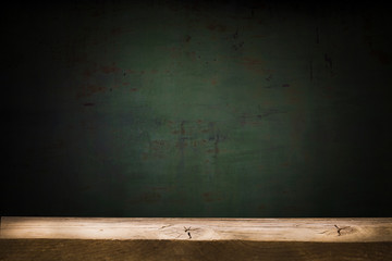 Old table top with brown concrete block wall in dark room background.