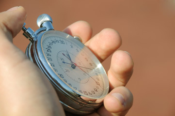 Stopwatch in hand on a background of a treadmill.