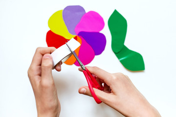 How to make a flower at home from colored paper. Hands make a colorful flower out of paper, scissors and pencil. Step 4. Gather the petals into a flower. Project for children DIY art. 