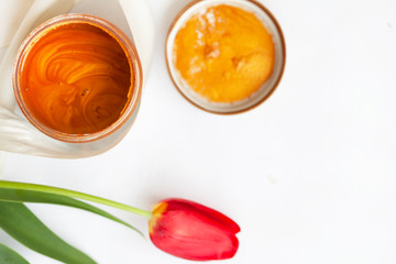Jar with cream and flowers on wooden background. Skin care cosmetics