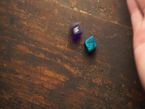 2D6 two Six sided dice being rolled on a heavy weathered old dark brown wooden surface background