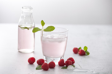 Glasses of raspberry infused water  with raspberries, ice and fresh mint leaves  on concrete background stone strong light with glass shadows. Copy space. 