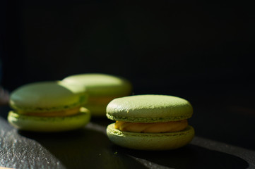 Black one-ton background and green French cakes with lime macaroons.