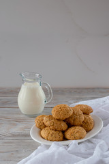 Oatmeal cookies with a jug of milk. On a wooden background.
