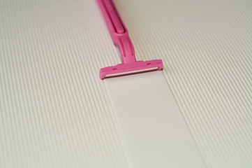 White shirked background with pink female razor for hair removal and dipilation.