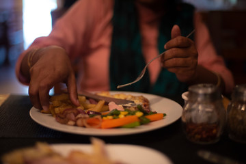 Blurred half face portrait of an Indian woman eating ice cream and brownie with a spoon inside a cafe or ice cream parlor. Indian lifestyle