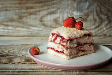 a piece of Napoleon cake with strawberries on a wooden background