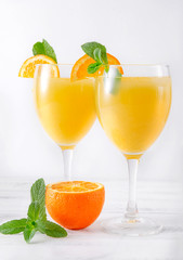 2 glasses of fresh orange juice with mint and ice, orange slices on a white, cocktail,