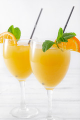 2 glasses of fresh orange juice with mint and cocktail tubes on a white background, cocktail,