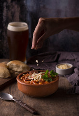 winter stew with grated cheese, bread and a beer in a rustic enviroment