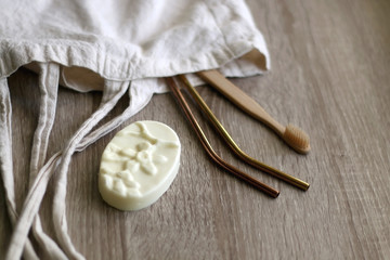 Canvas tote bag with zero waste products: bamboo toothbrush, reusable metal straws and soap. Selective focus.