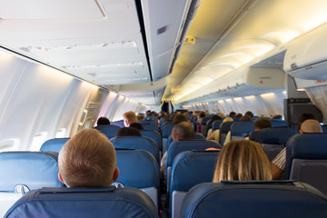 Interior of airplane with passengers on seats waiting for take off from airport. Vacation concept