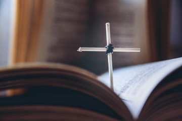 Open Holy Bible book and homemade cross, close-up view