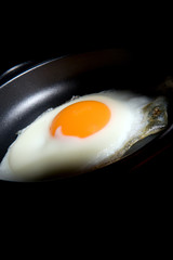 fried egg with cutting light on black background with copy space