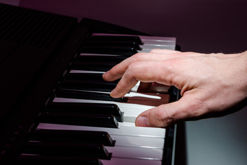 The musician plays the keyboard of the synthesizer with the keys of the piano. At a concert with...