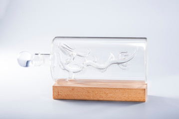 A glass wine bottle with a dragon sculpture inside