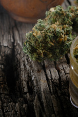 cannabis buds lie on an old wooden board. near part of the grinder. vertical