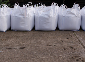 Row of white plastic sand bags with concrete in foreground