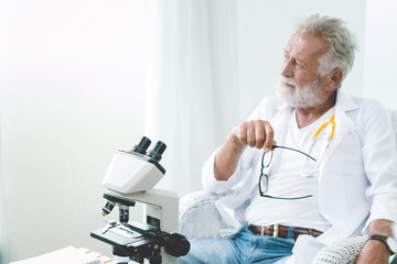 Professional doctor elderly thinking faraway look serious mood think of ways to cure the Corona...