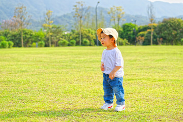 The little boy in a hat in the outdoor lawn

