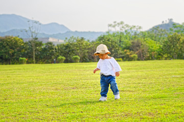 Naklejka na ściany i meble The little boy in a hat in the outdoor lawn 