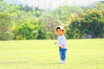 The little boy in a hat in the outdoor lawn
