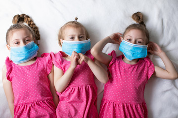 Little children girls in pink dresses in blue medical masks. Global quarantine. Protection against...