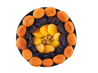 Dried apricots, prunes and golden raisins laid out in circles on black plate isolated on white background top view. Healthy snack.