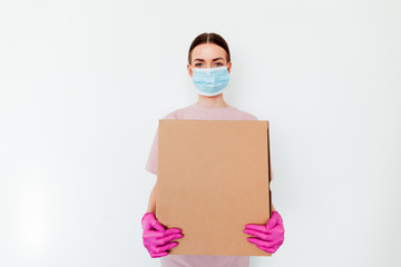 Fototapeta na wymiar Delivery during coronavirus outbreak. Copy space. Delivery woman holding cardboard boxes in medical rubber gloves and mask on white background. Online shopping and Express medical delivery . 
