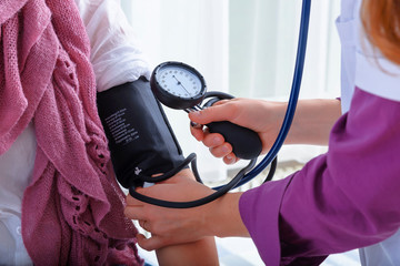 female doctor examines woman's blood pressure