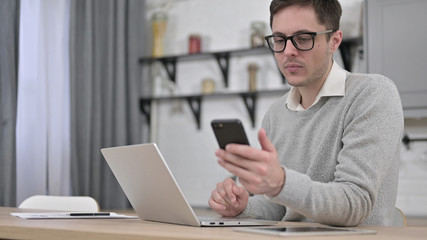 Young Man using Smartphone and Laptop