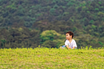 A little boy sitting on the grass