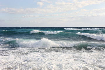 sea waves on the surface of sea water during strong winds and bad weather, sunny day, sky with clouds.