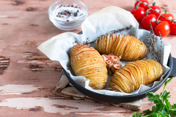 Hasselback potatoes. Baked potatoes in pan on wooden table