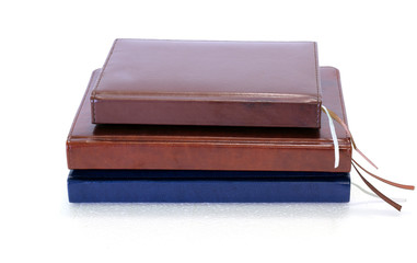 A stack of hardcover diaries or planners with bookmarks on a white background. Side view from the side of the book spine.