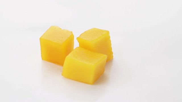 Ripe mango slice cubes rotating on white background