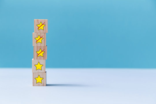 Rating for service quality. Customer experience concept. Wooden blocks. Crossed out stars. Copy space. Isolated on blue