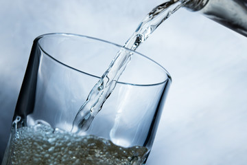 pouring lemonade drink into a transparent glass on a white background